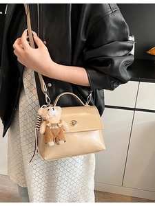 Glossy cream leather crossbody bag with gold twist lock and cute plush bear charm