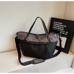 Detail of crossbody travel bag with black nylon fabric, grey grid pattern and orange cords