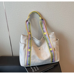 Detail showing high-capacity canvas tote bag with colorful woven strap and side pocket