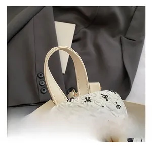 Detail of white mini backpack showing black bow patterns and gold metal zipper closure