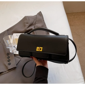 Detail of a black leather square bag with gold metal twist lock and three front pockets