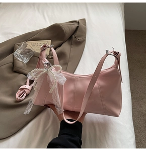 Close-up of light pink shoulder bag featuring lace bow and pearl charm details