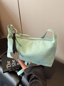 Minimalist mint green suede hobo bag with silver heart pendant and black knot detail