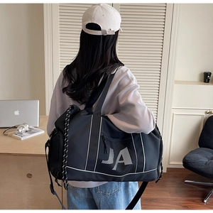 Seitenansicht der großen schwarzen Reisetasche mit JA-Logo und Netztasche auf der Schulter