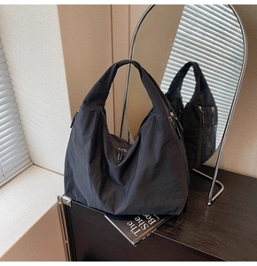 Detailed view of black nylon tote bag featuring multi-pocket design and wide handle