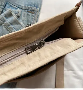 Dettaglio della cerniera in metallo argentato e delle cuciture sulla borsa tote beige