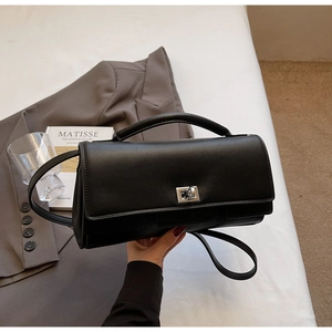 Detail of a black leather mini square bag featuring a silver twist lock and sleek handle
