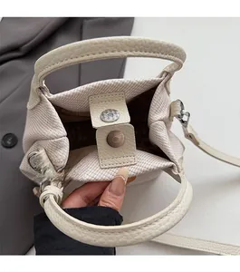 Detail view of the beige woven handbag featuring a secure magnetic snap closure design