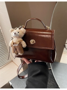 Brown oil wax leather handbag with gold twist lock and a cute plush bear charm