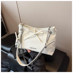 Detail of a beige chain shoulder bag with decorative bow and metal logo on smooth leather