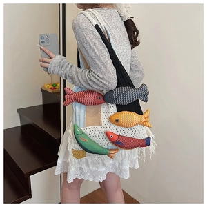 Detailed close-up of a handmade crochet shoulder bag with colorful fish patches and long tassels