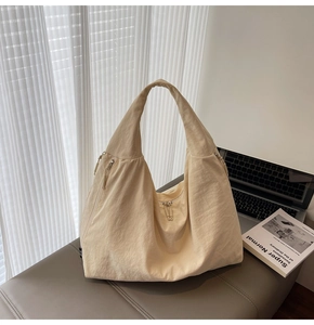 Detail of beige oversized tote bag with natural pleated texture and wide shoulder strap
