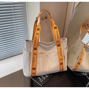 Detail of beige canvas tote bag with orange floral strap and metal magnetic buckle closure
