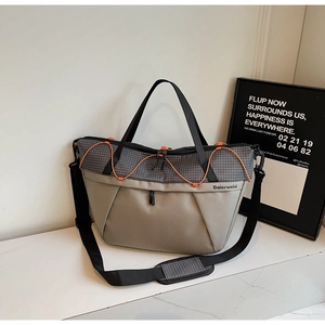 Detail of grey sports tote bag with orange elastic cords and adjustable shoulder strap