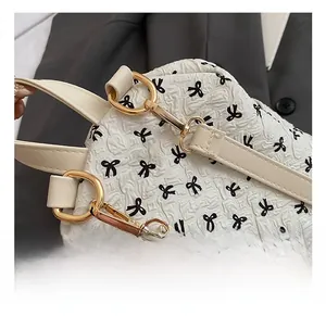 Close-up of bright gold metal hook and black ribbon jacquard pattern on a white backpack