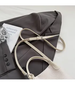 Detail view of the adjustable leather shoulder strap and metallic buckle on the bag