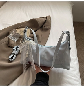 Detail of pale blue bag featuring large pearl bow decoration and white lace accents