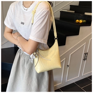 Détail du sac seau jaune clair avec texture plissée et pendentif sphère argentée
