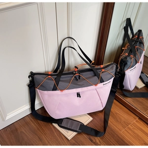 Detail of pink and grey checkered travel bag with orange cords and padded shoulder strap