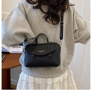 Detailed view of black litchi pattern leather bag with adjustable strap and top handle