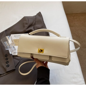 Detail view of cream leather handbag featuring golden twist lock and front pockets