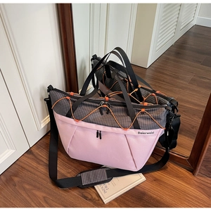 Detail of pink and grey sports travel bag with orange bungee cords and black handles