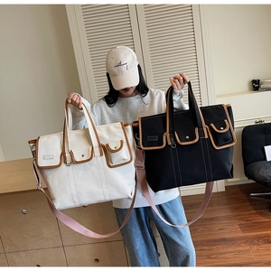 Détail du sac en toile bicolore avec bordure en cuir marron et poches latérales utiles
