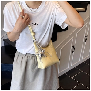 Gros plan du sac seau en cuir verni jaune clair avec grand pendentif étoile argenté