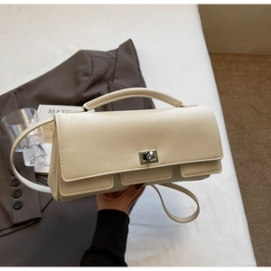 Detailed view of cream leather handbag featuring silver twist lock and minimalist design