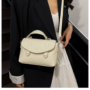 Close-up of beige lychee grain leather handbag with silver hardware and top handle