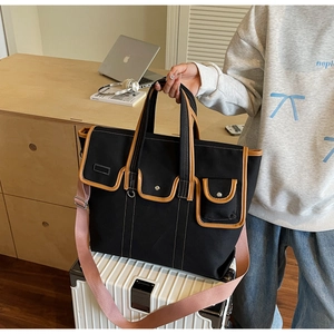 Détail du sac en toile avec garniture en cuir et bandoulière tissée rose sur un bagage
