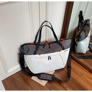 Detail of grey checkered and white panels on large gym bag with orange drawstring cord