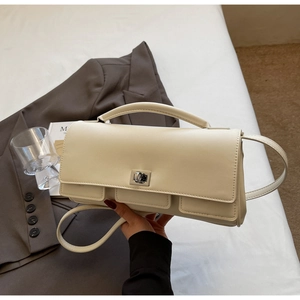 Detail of cream square handbag with silver twist lock and textured faux leather finish