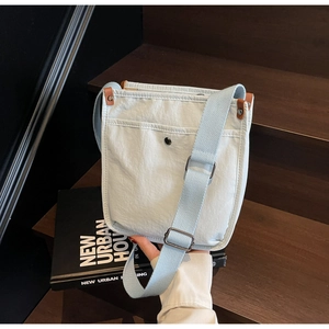 Dettaglio borsa tote in tela azzurra con tasca frontale e tracolla regolabile