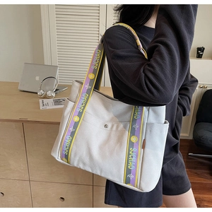 Detail of canvas tote bag with contrast yellow and purple lettered shoulder straps