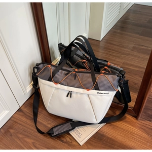 Detail of grid pattern travel bag with orange elastic cords and adjustable strap