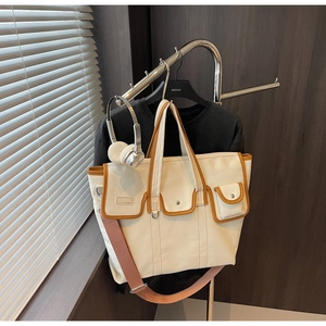 Détail du sac en toile avec poches bordées de cuir marron et bandoulière rose chic