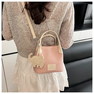 Detail of pink plaid bucket bag with ivory leather elephant charm on a model