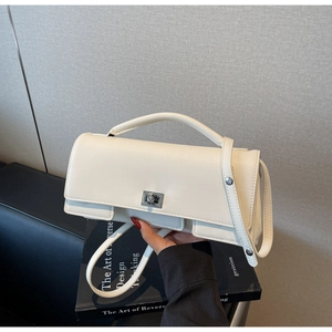 Detailed macro view of cream square leather handbag featuring a silver twist lock closure