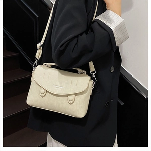 Detail of cream white lychee texture crossbody bag with metal hooks and adjustable strap