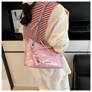 Pink patent leather shoulder bag detail with metal chain strap and bow decoration