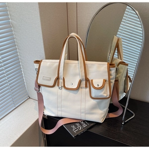 Détail du sac en toile avec bordure en cuir brun, poches et bandoulière rose