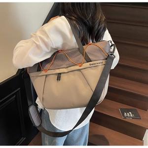 Detail view of khaki and grey checkered gym bag with orange decorative cord and shoulder strap