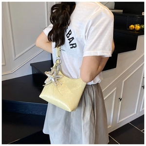 Gros plan d'un sac seau jaune crème avec breloque étoile de mer argentée en studio