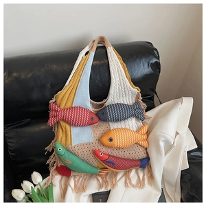 Detail of creative knit tote bag featuring 3D fish dolls and fringe on leather sofa