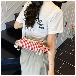Detail view of the red and white checkered candy-shaped bag with lace trim and chain strap