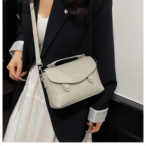 Close-up of cream lychee texture leather shoulder bag with decorative buttons and hand strap