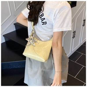 Détail du sac hobo jaune clair en cuir brillant avec pendentif étoile de mer argenté