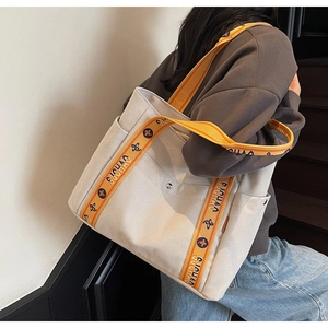Close-up of canvas tote bag featuring orange strap with GUCHAO text and side pocket