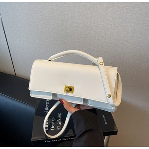 Close-up of a white envelope bag with a golden square twist lock and fine leather texture